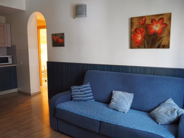 Divano blu in soggiorno con quadro sulla parete, appartamenti I Narcisi